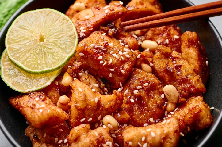 Korean Sweet Fried Chicken Dakgangjeong in black bowl. Dakgangjeong is korean cuisine dish with deep fried crunchy chicken in sweet sauce. Korean Food. Close up
